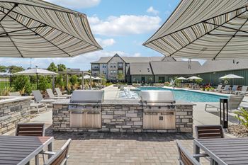 A resort style pool with a grill and umbrellas